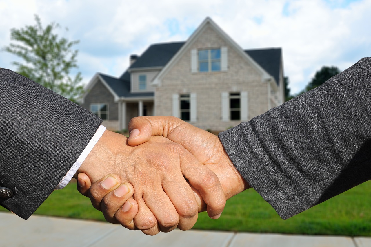 Handshake in front of a house representing trust, partnership, and successful real estate transactions.